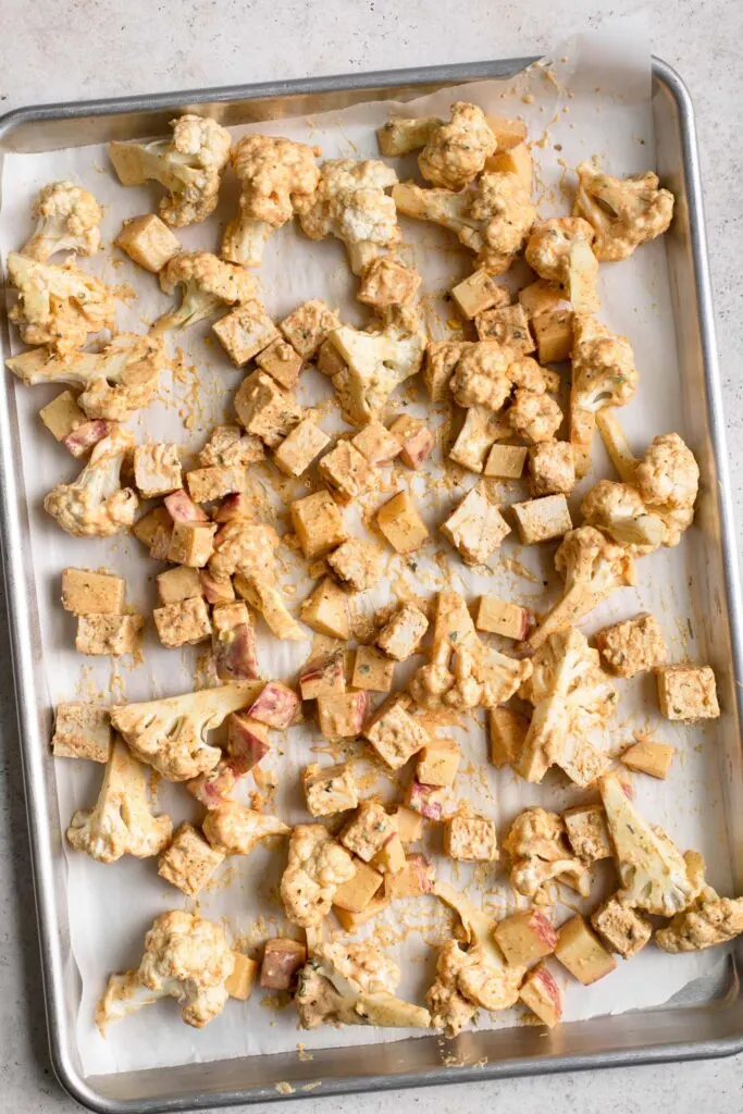 tofu, cauliflower, and potato spread over baking sheet before baking