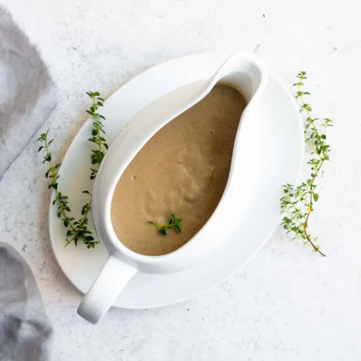 creamy vegan mushroom gravy in a gravy boat garnished with fresh thyme