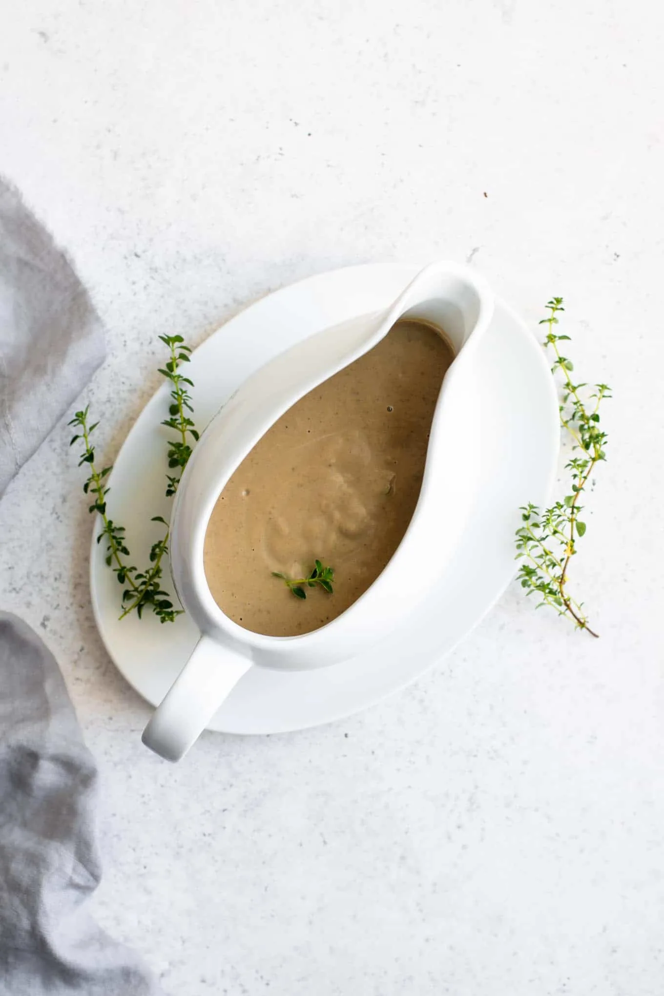 creamy vegan mushroom gravy in a gravy boat garnished with fresh thyme