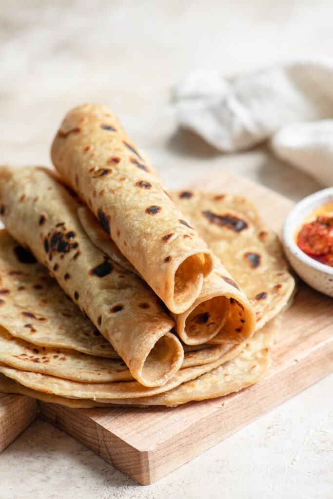 three roti rolled up sitting on top of stack of roti