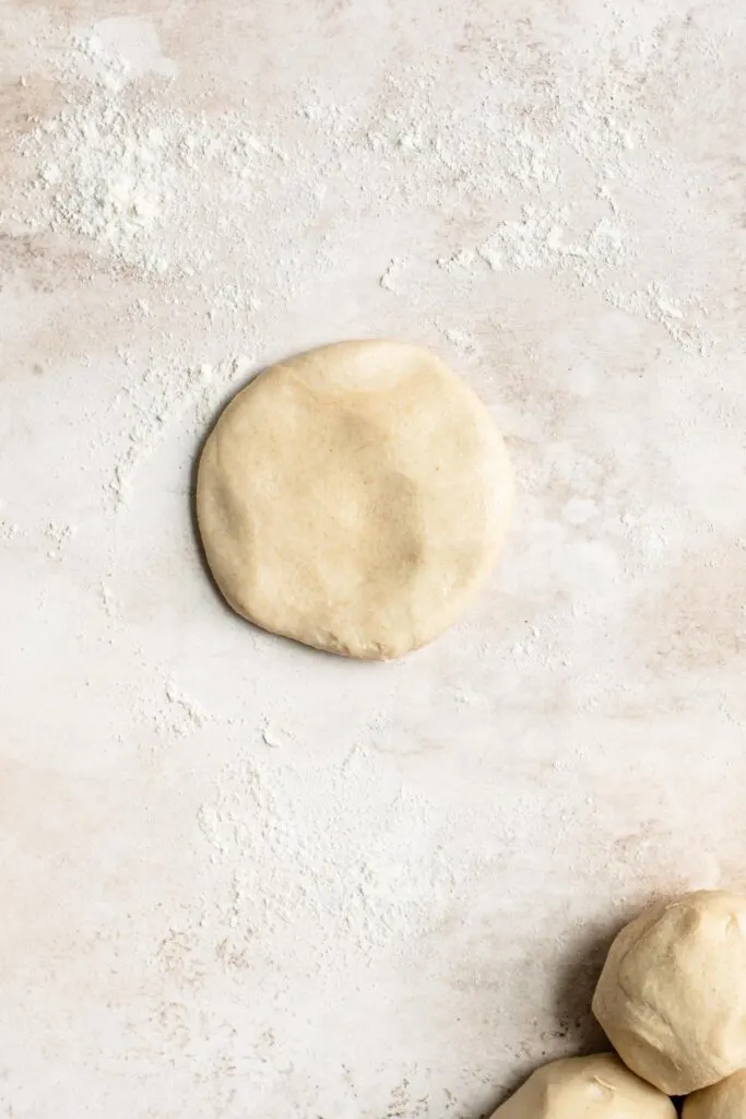 dough ball flattened by hand into a disk