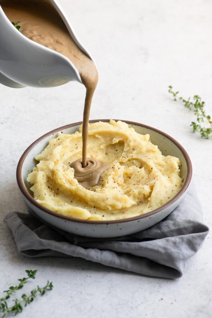 pouring gravy over mashed potatoes