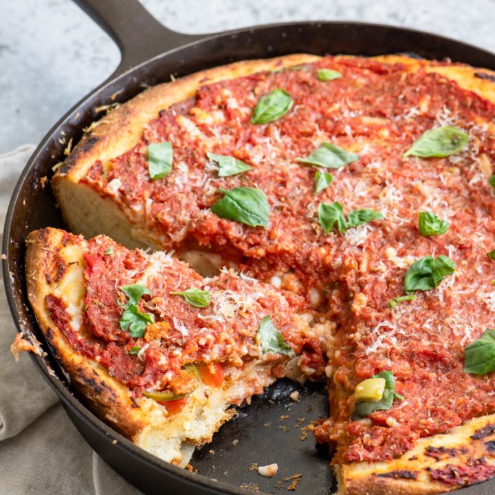 Deep dish pizza with one slice removed and a second cut in the pan