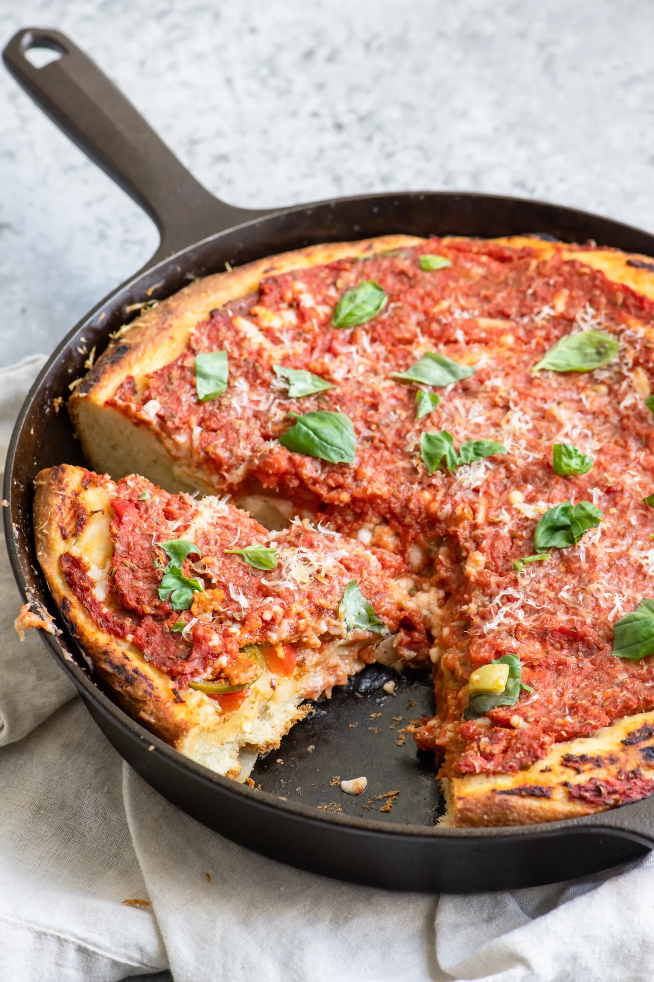 Deep dish pizza with one slice removed and a second cut in the pan
