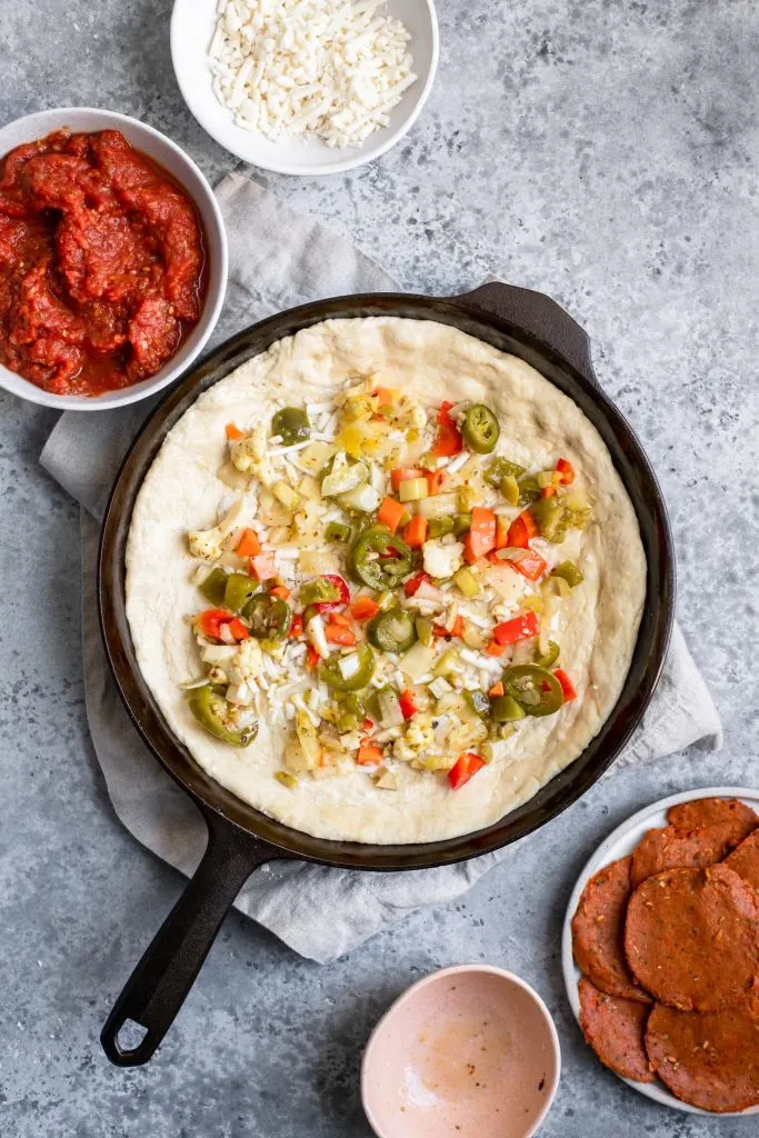 assembling deep dish pizza: giardiniera added to pizza