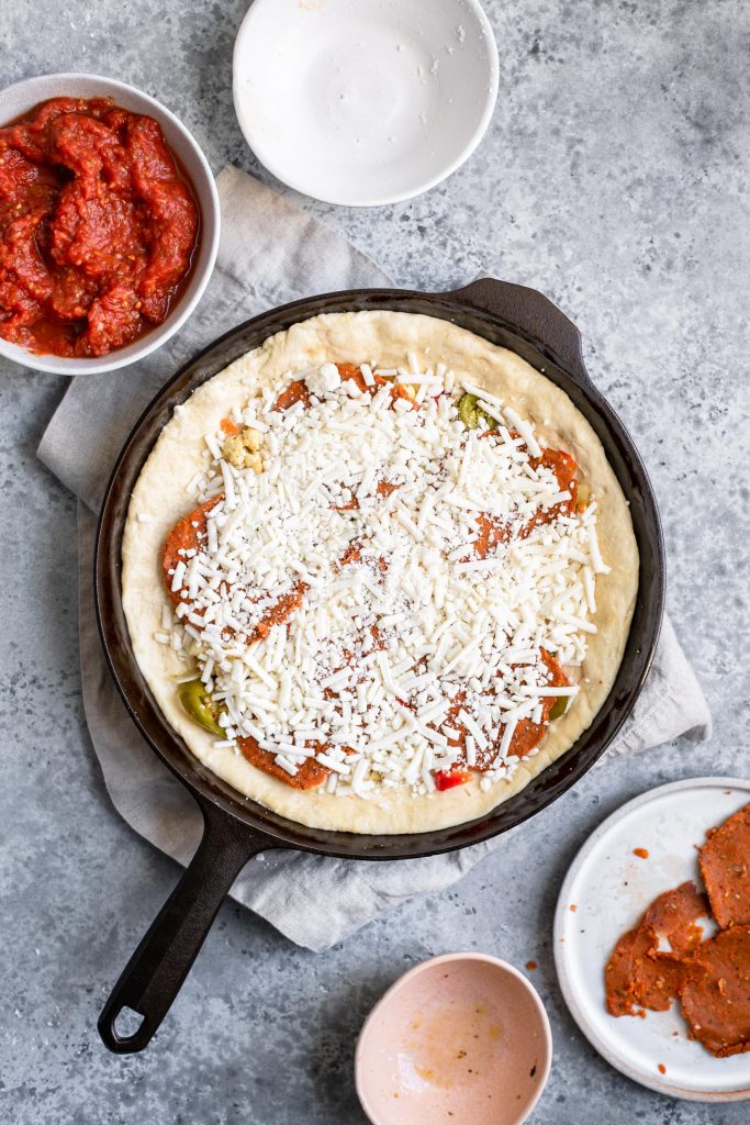 assembling deep dish pizza: the rest of the cheese is put on top of the filling