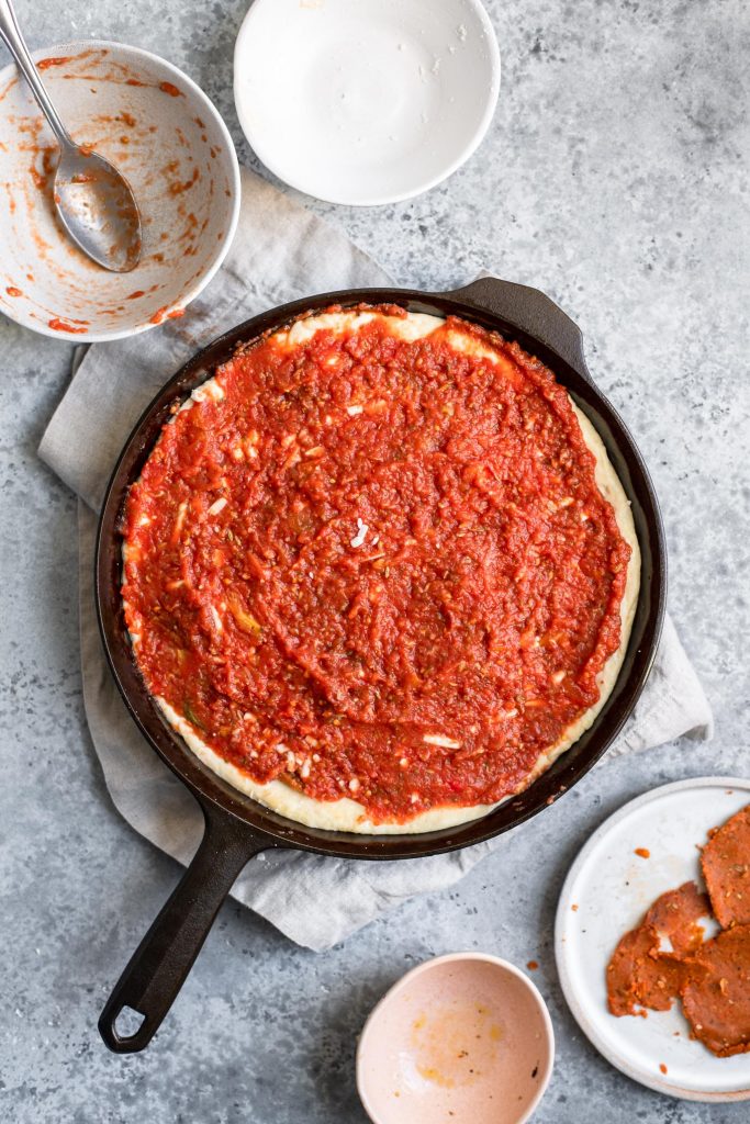 assembling deep dish pizza: rest of sauce is spread over top
