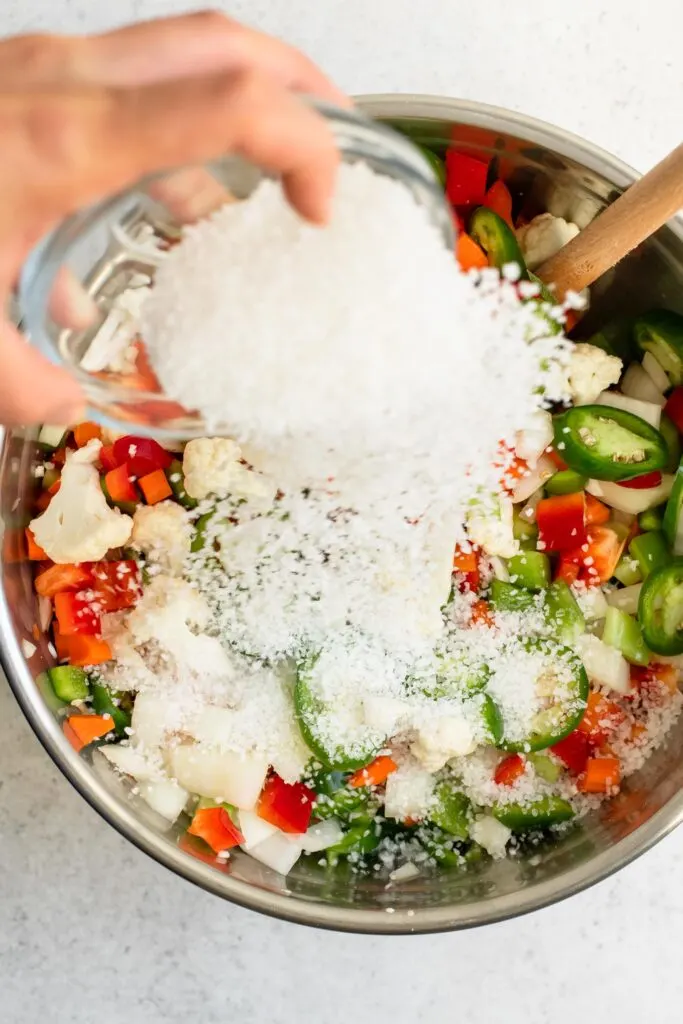tossing kosher salt onto the cut vegetables for giardiniera