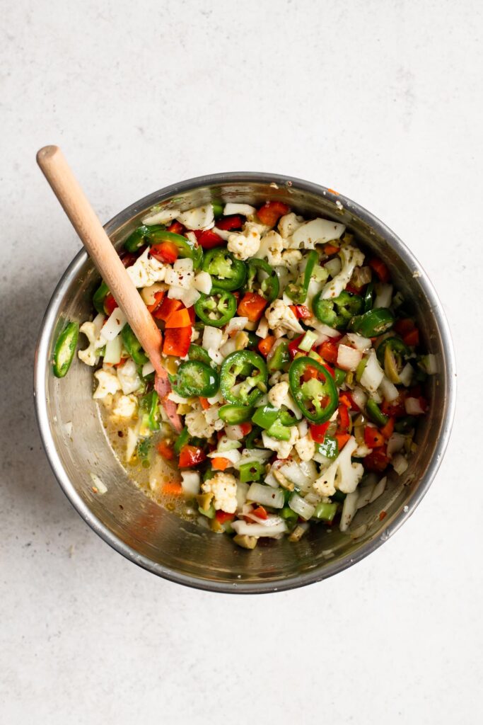 dressing and giardiniera vegetables mixed together in mixing bowl