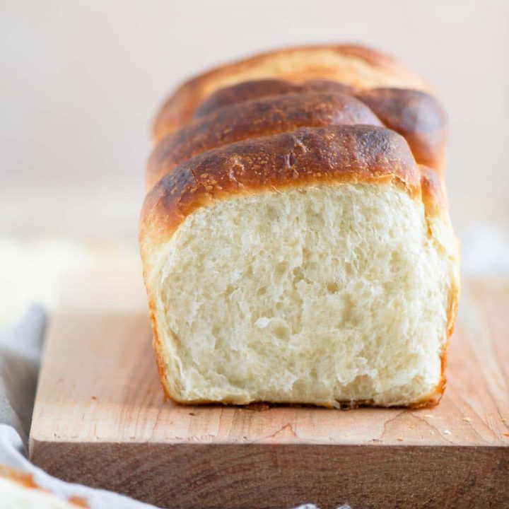 segment shaped vegan brioche on cutting board with one segment pulled off to show the soft texture