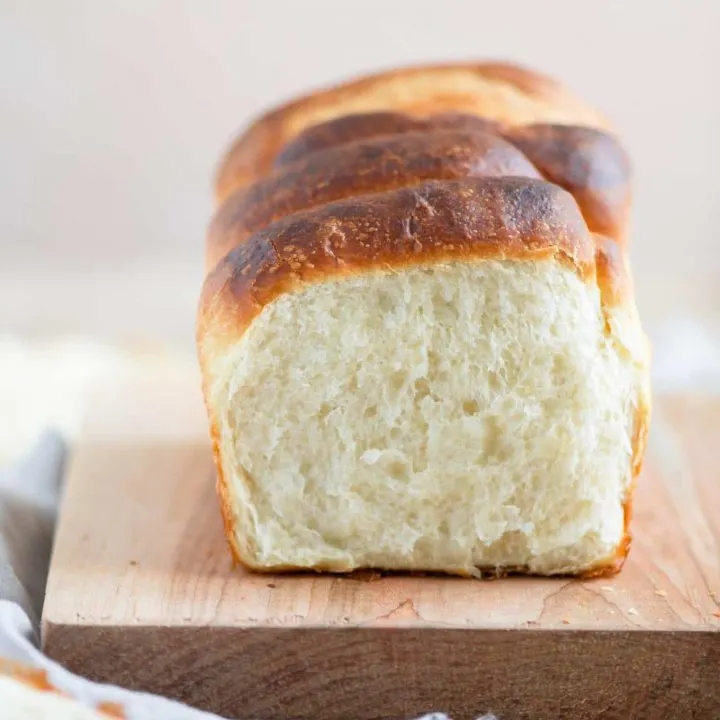 segment shaped vegan brioche on cutting board with one segment pulled off to show the soft texture