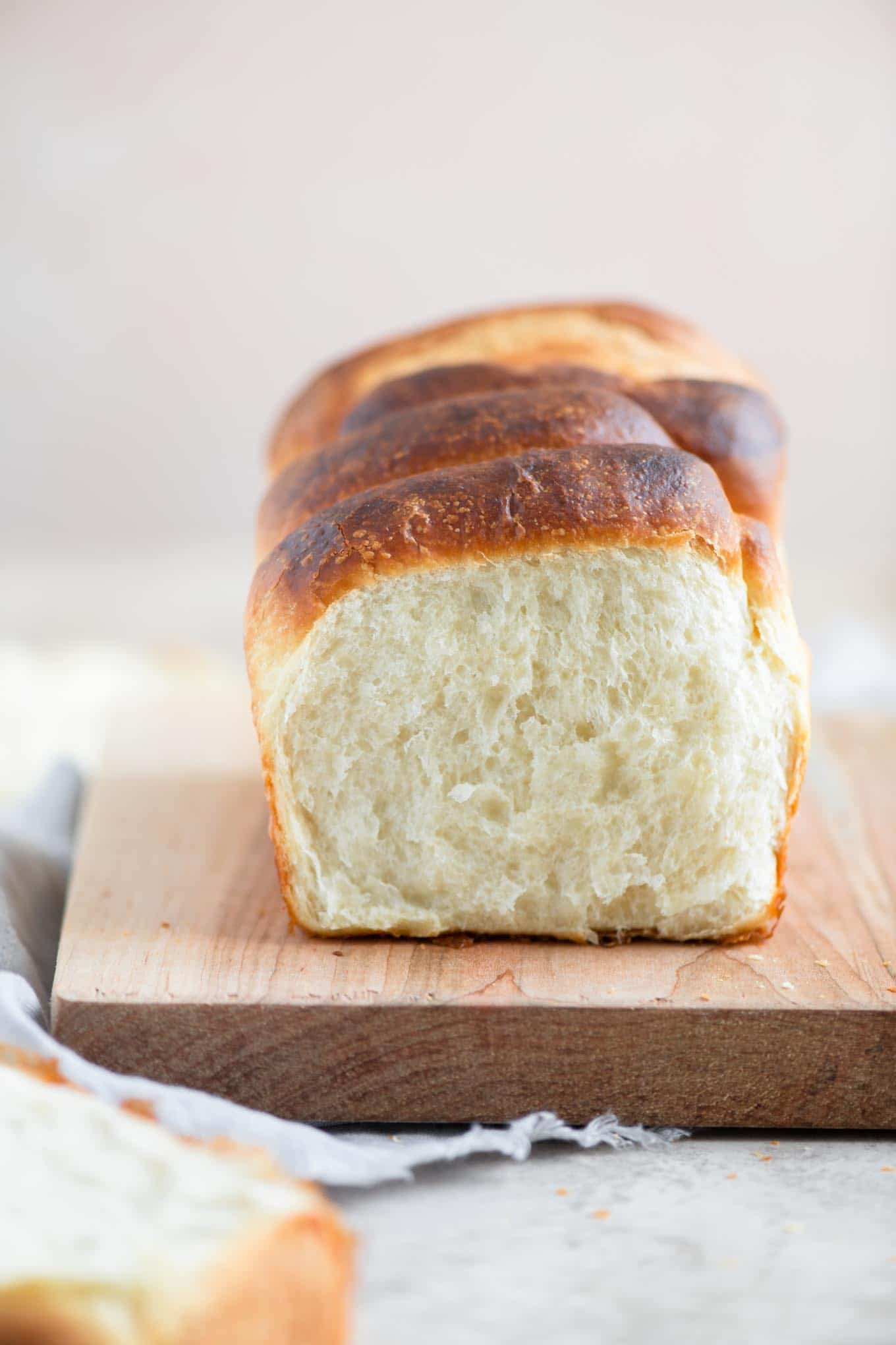 segment shaped vegan brioche on cutting board with one segment pulled off to show the soft texture