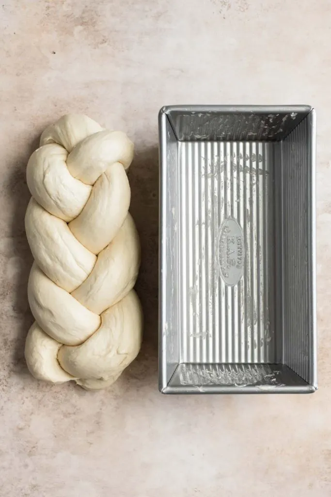 braided brioche with ends tucked in next to greased loaf pan