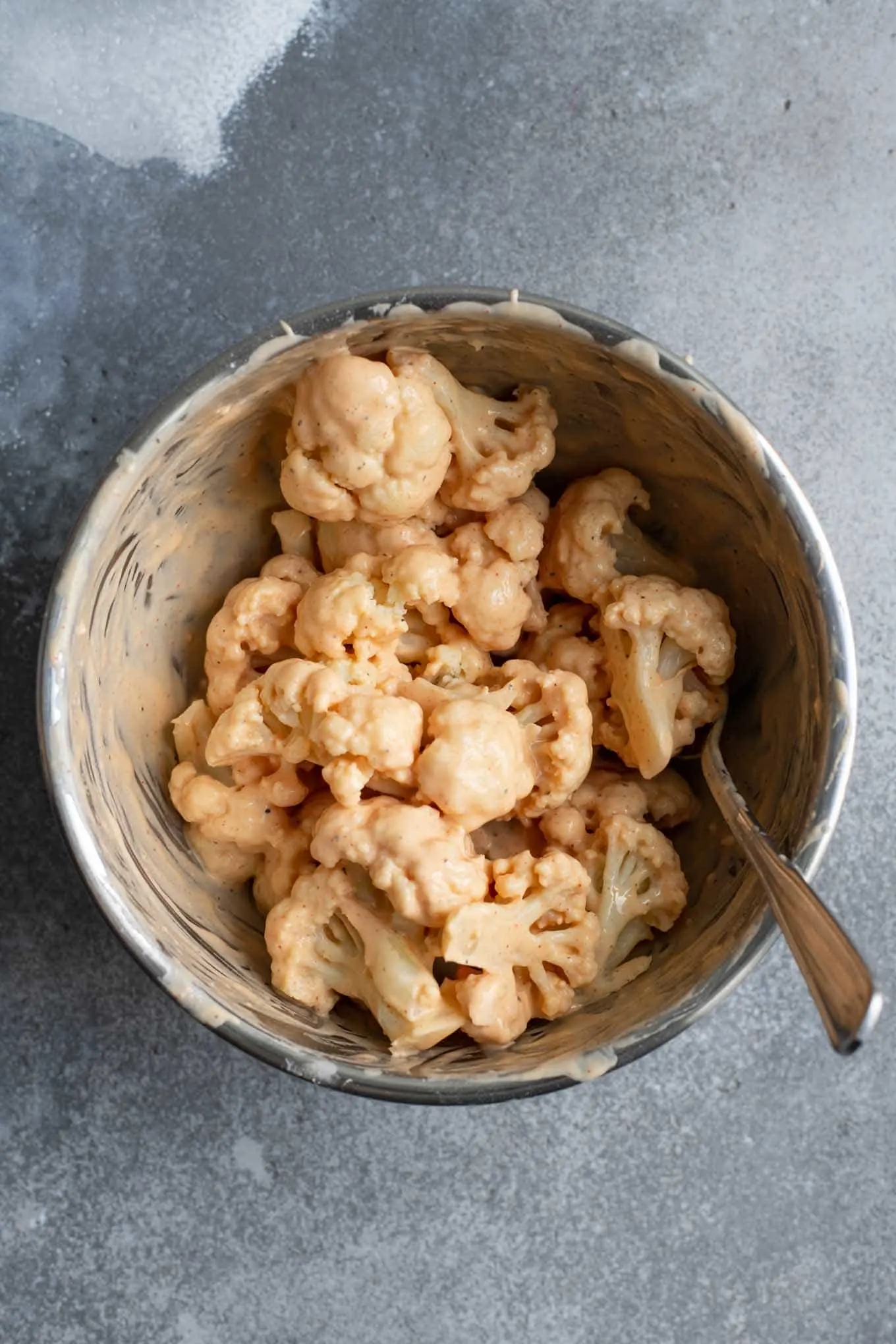 cauliflower tossed in the gobi manchurian batter in a mixing bowl