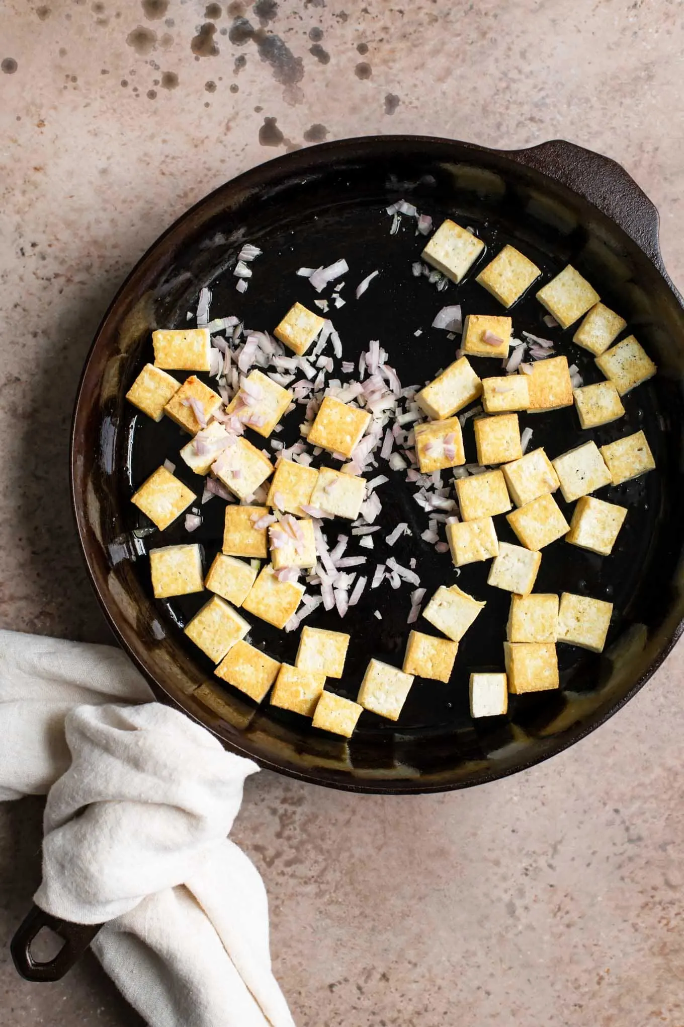 pan fried tofu with shallot added in skillet