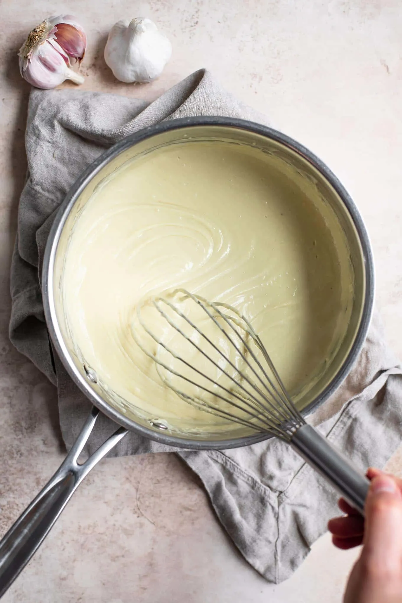 Vegan creamy garlic sauce being whisked in the pot