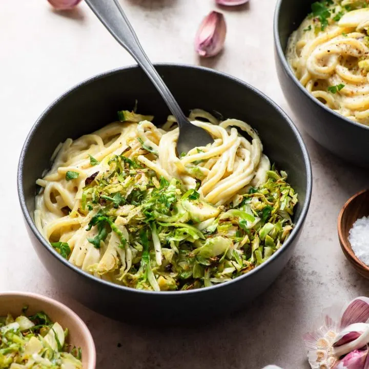 vegan creamy pasta topped with shaved brussels sprouts served in bowls