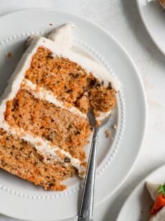 slice of vegan carrot cake on a plate with a fork taking a piece out of the corner