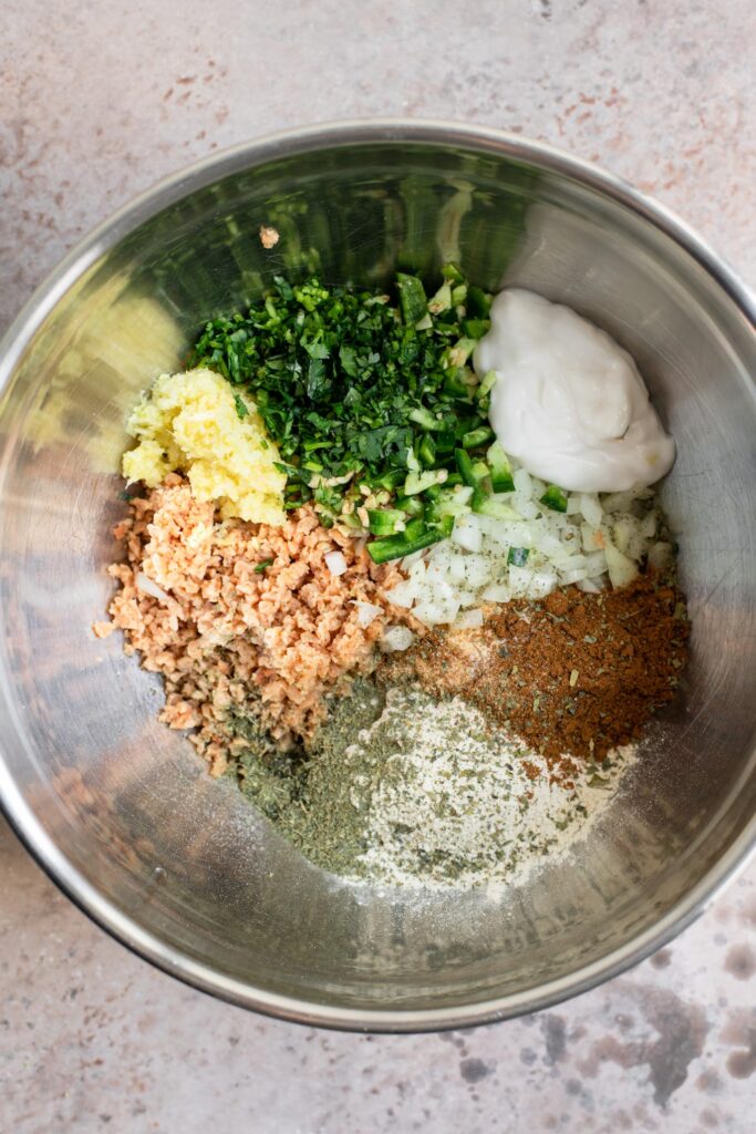 Ingredients for kabab combined added to a mixing bowl, before mixing together