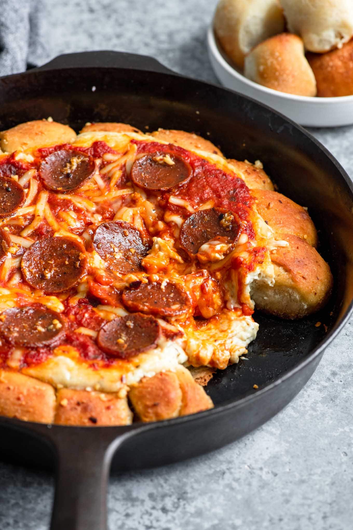 pizza dip with a couple of garlic rolls taken off and the dip center oozing into the space