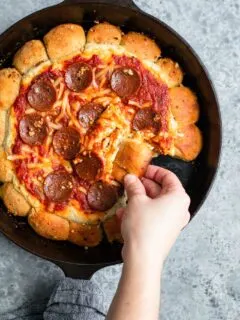 scooping up a bite of vegan skillet pizza dip