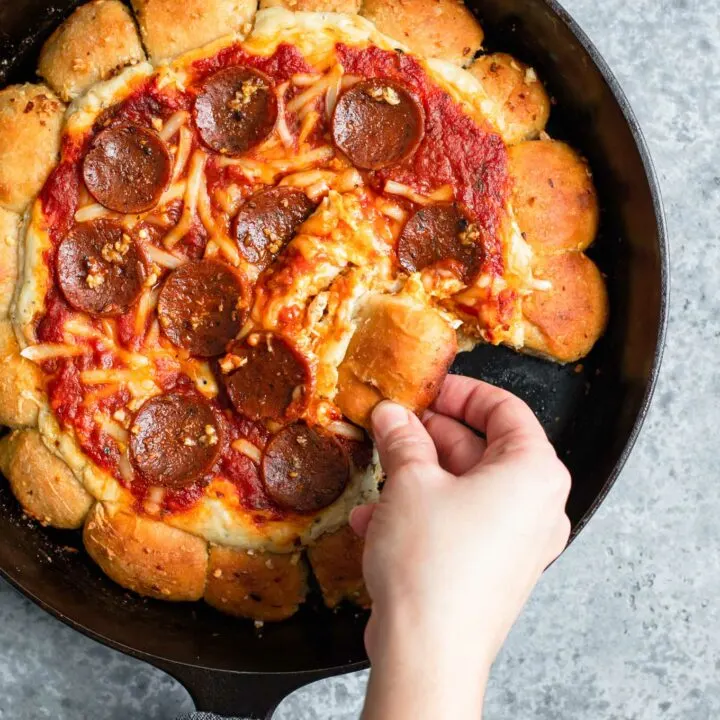 scooping up a bite of vegan skillet pizza dip