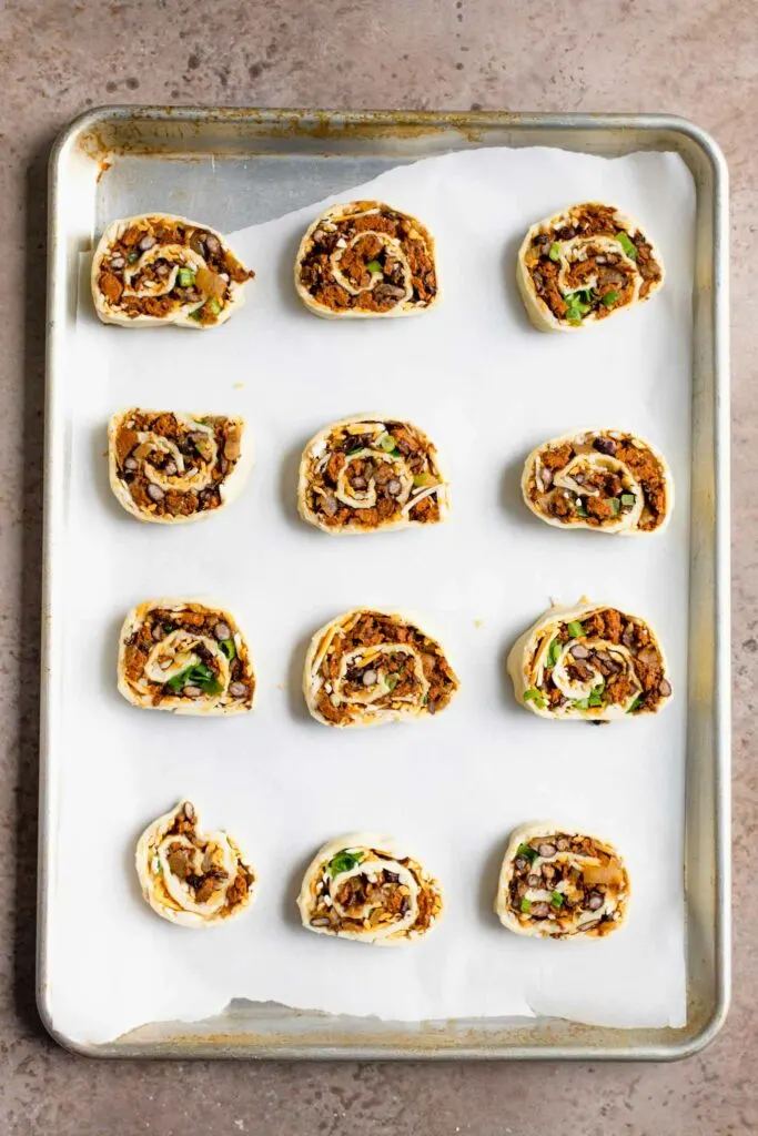vegan pinwheels on parchment lined baking tray before baking