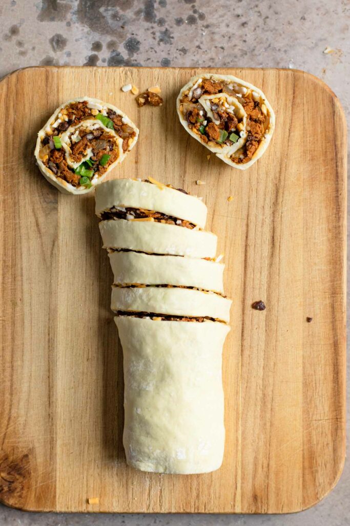 vegan pinwheel roll on cutting board with 6 slices, two resting flat