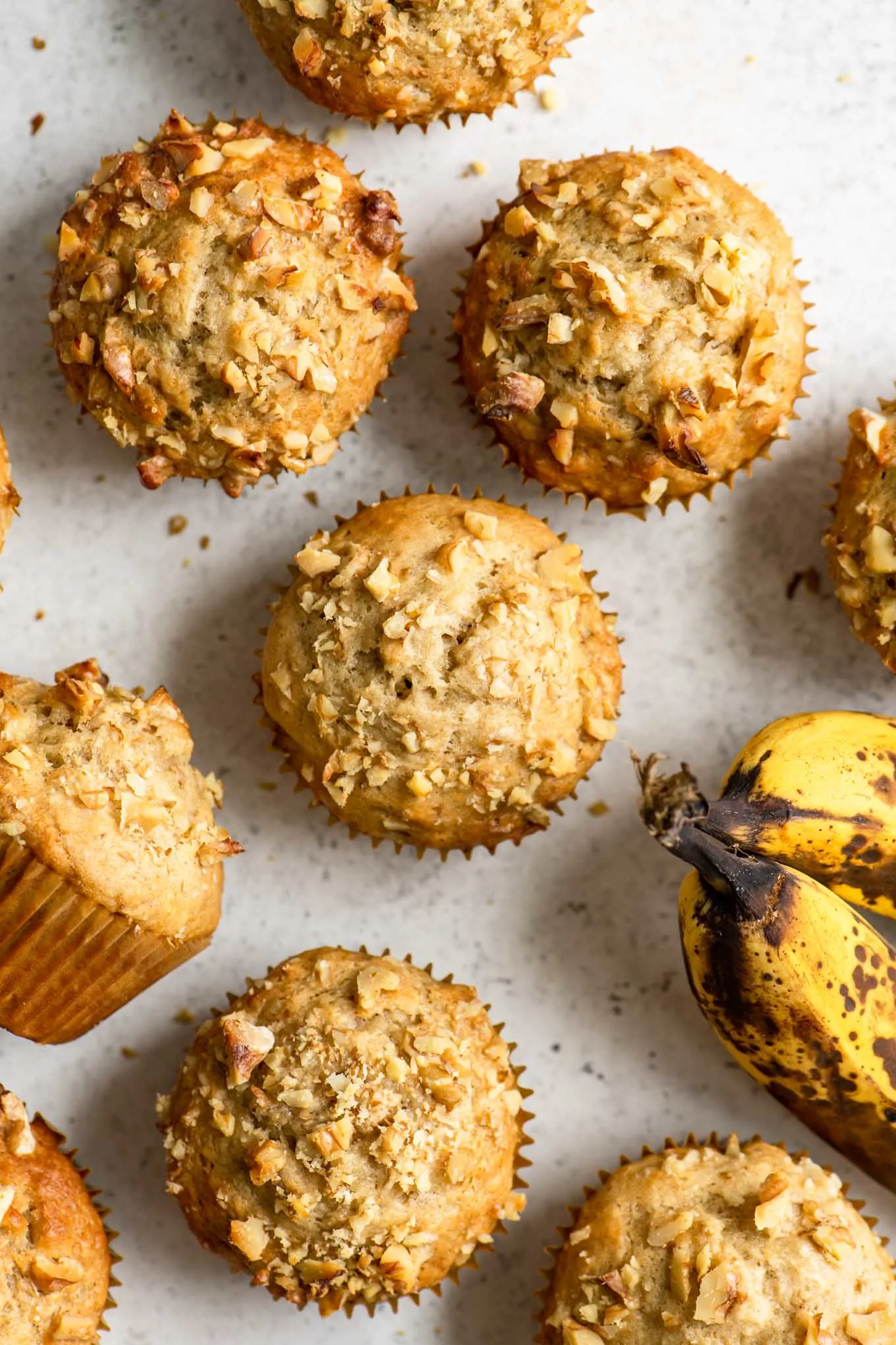 overhead of vegan banana nut muffins with two ripe bananas peeking in the side