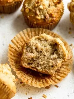 angled view of vegan banana nut muffin unwrapped and broken in half to show the soft crumb