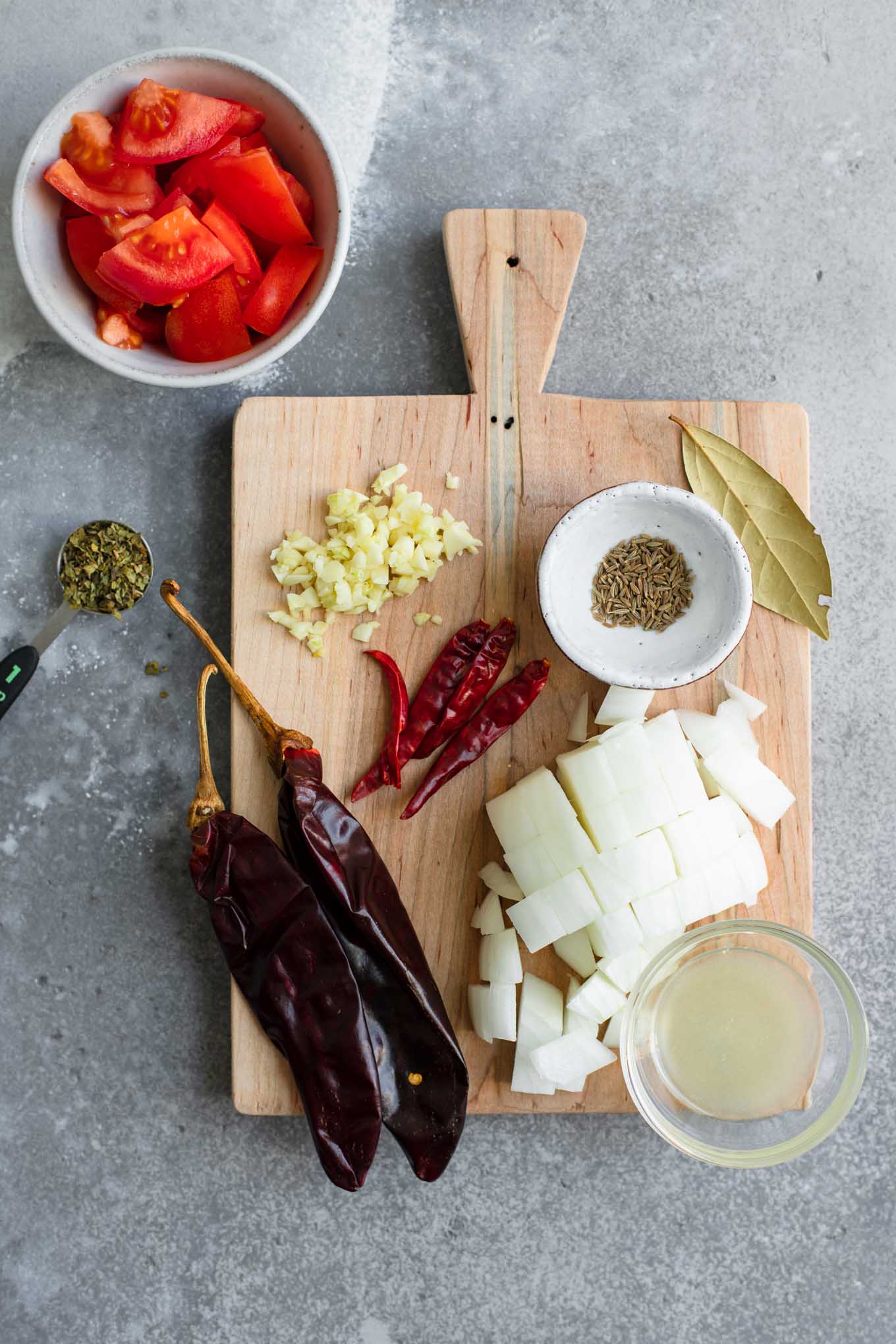 ingredients for the barbacoa sauce: guajillo chiles, chiles de arbol, chopped onion, cumin seed, bay leaf, Mexican Oregano, lime juice, garlic, and chopped tomato