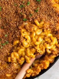 close up of vegan berbere mac and cheese with half of it covered with injera crumb topping and other half showing the cheesy noodles