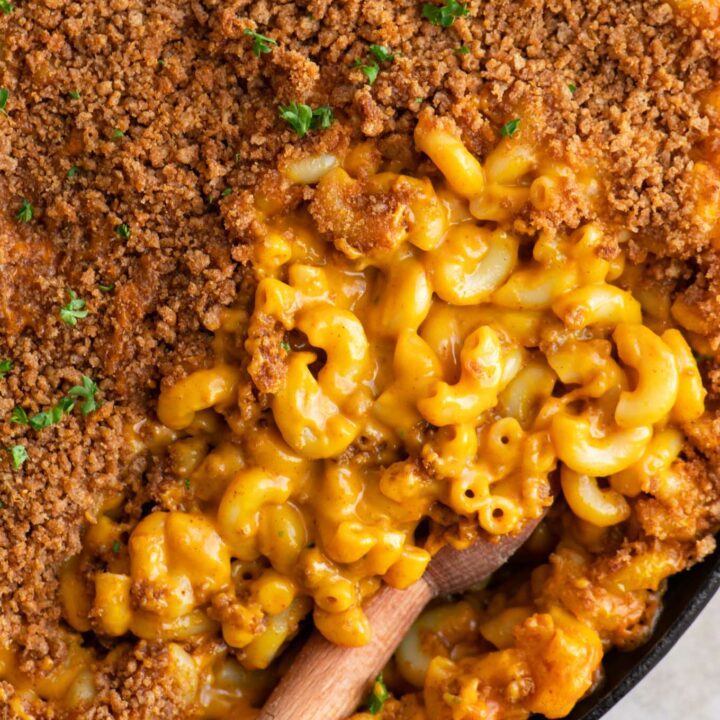 close up of vegan berbere mac and cheese with half of it covered with injera crumb topping and other half showing the cheesy noodles