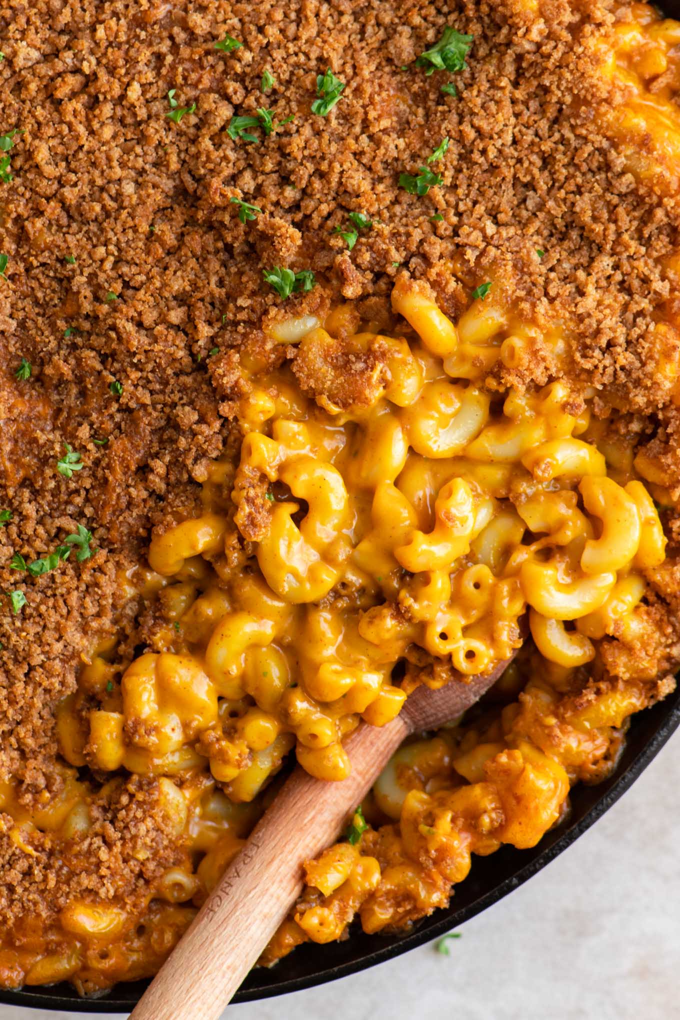 close up of vegan berbere mac and cheese with half of it covered with injera crumb topping and other half showing the cheesy noodles