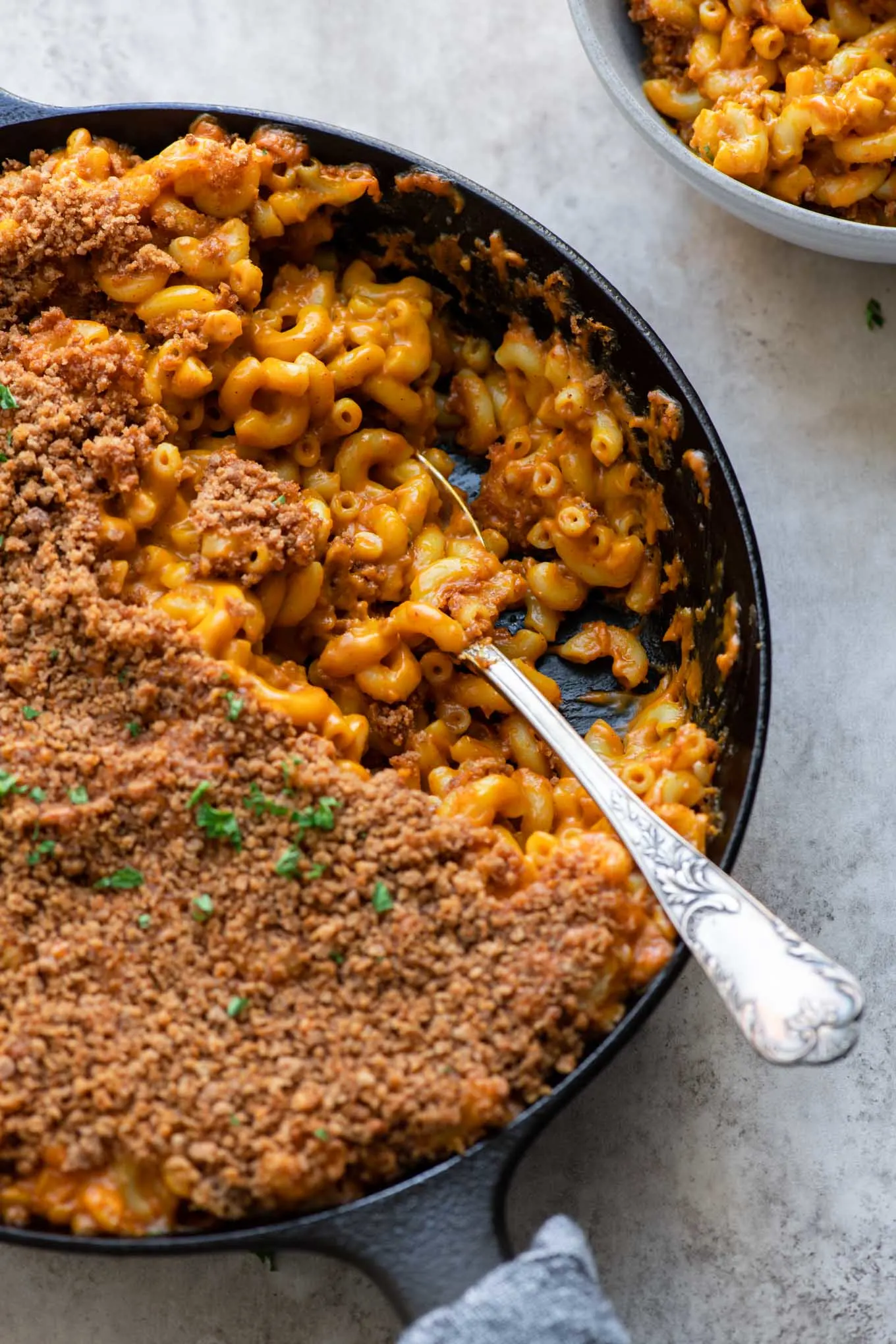 side view of mac and cheese with one serving scooped into a bowl