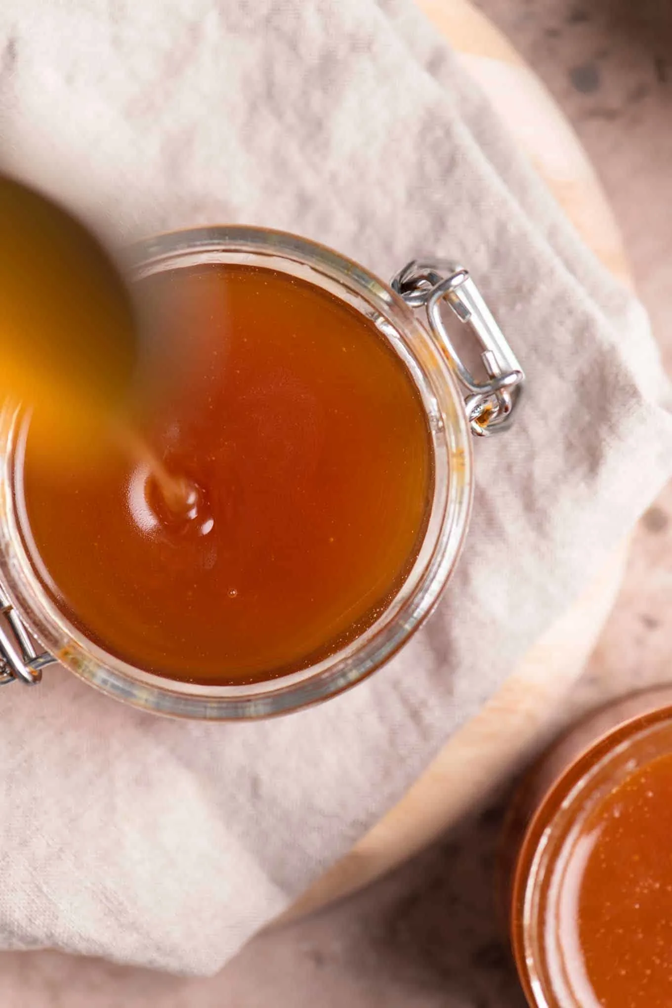 overhead of caramel sauce dripping off spoon back into jar