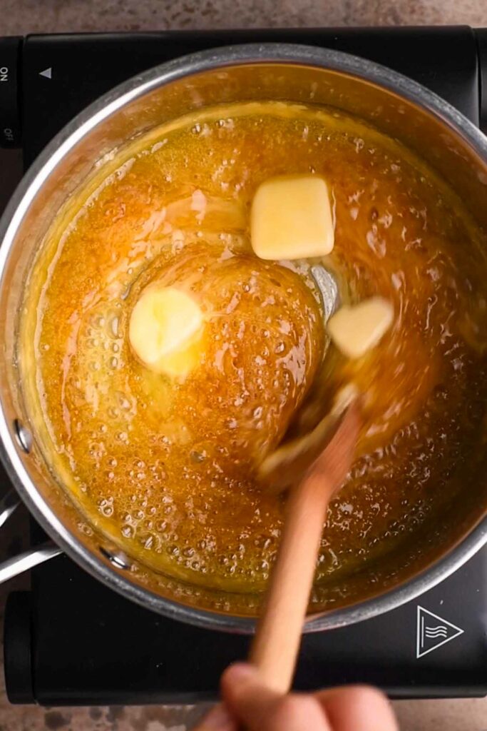 vegan butter being stirred into melted sugar with wooden spoon