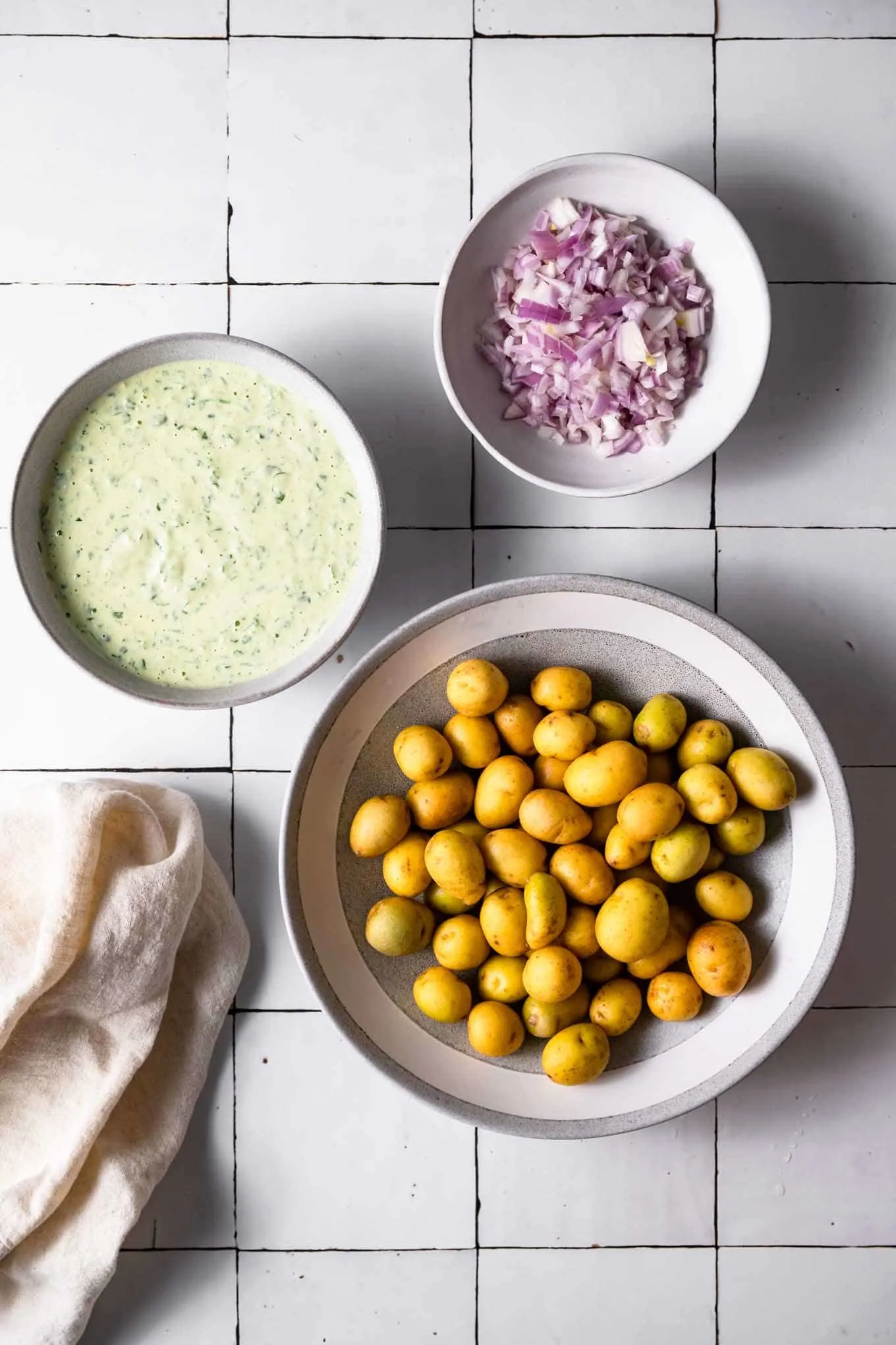 baby potatoes, dressing, and minced shallot in bowls