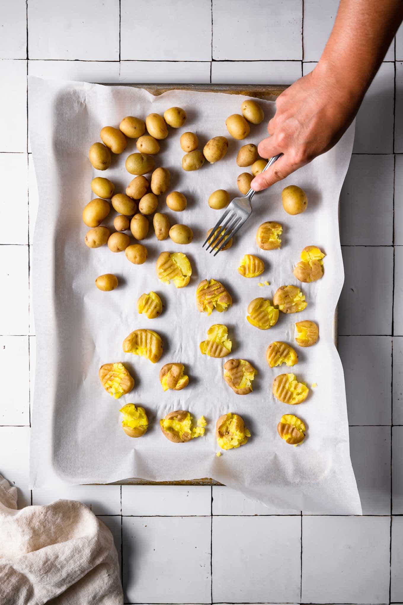 smashing boiled baby potatoes on baking tray