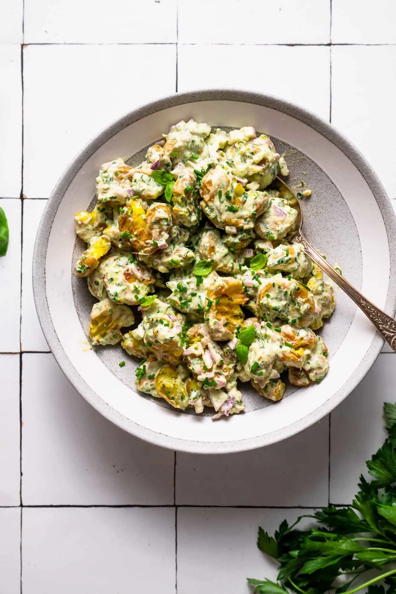 bowl of smashed potato salad on tile background