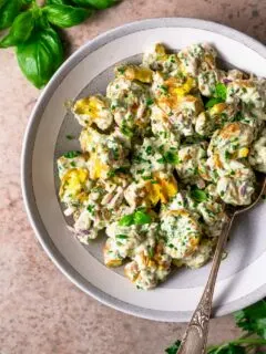 herbed smashed potato salad in bowl with basil and parsley sprigs in edge of photo