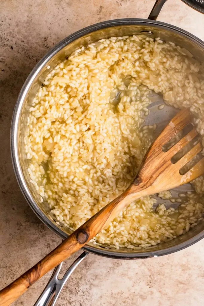 risotto cooking in pot with half of the vegetable broth added to the corn