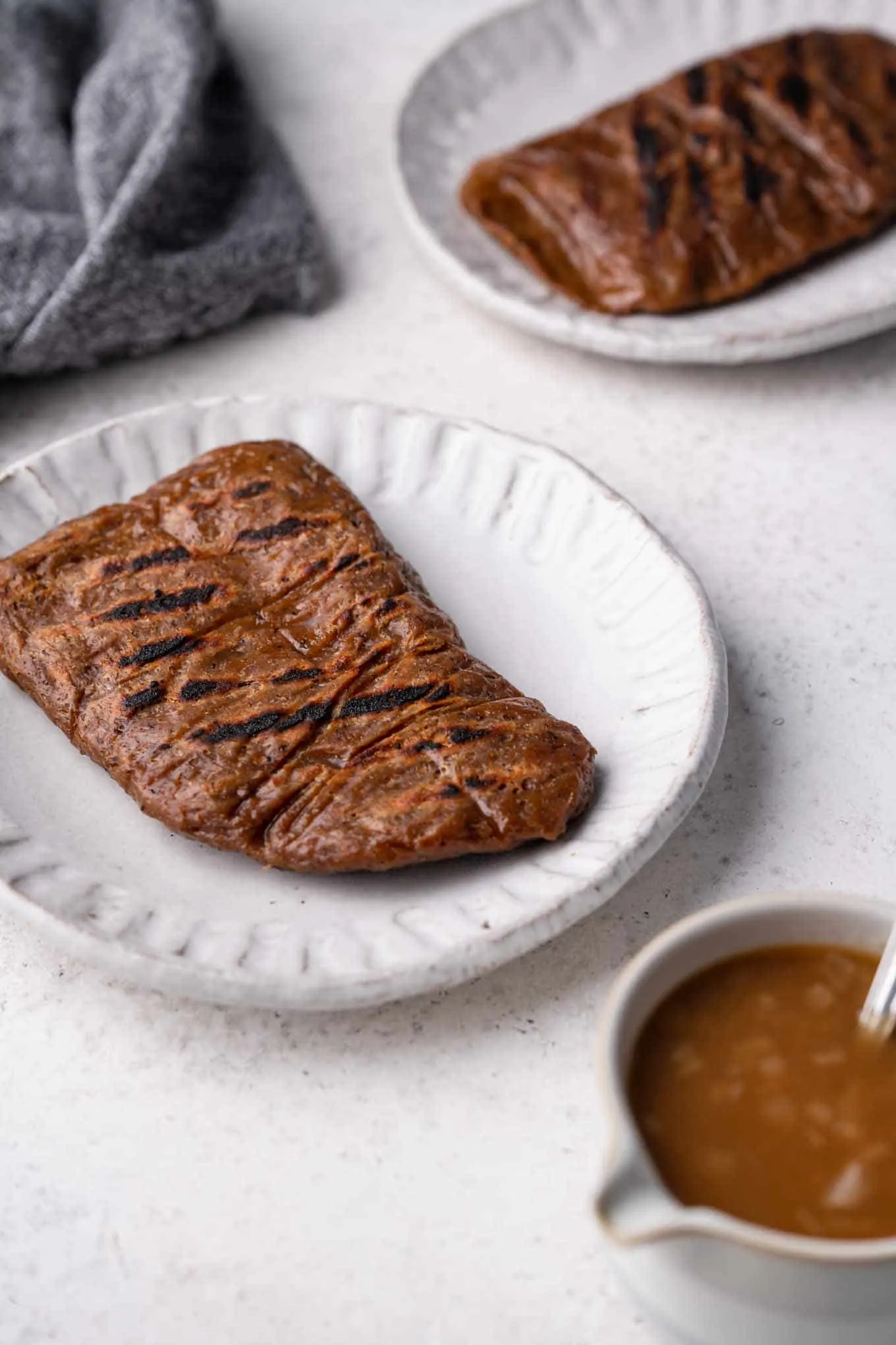 grilled seitan steaks on plates with a side of gravy