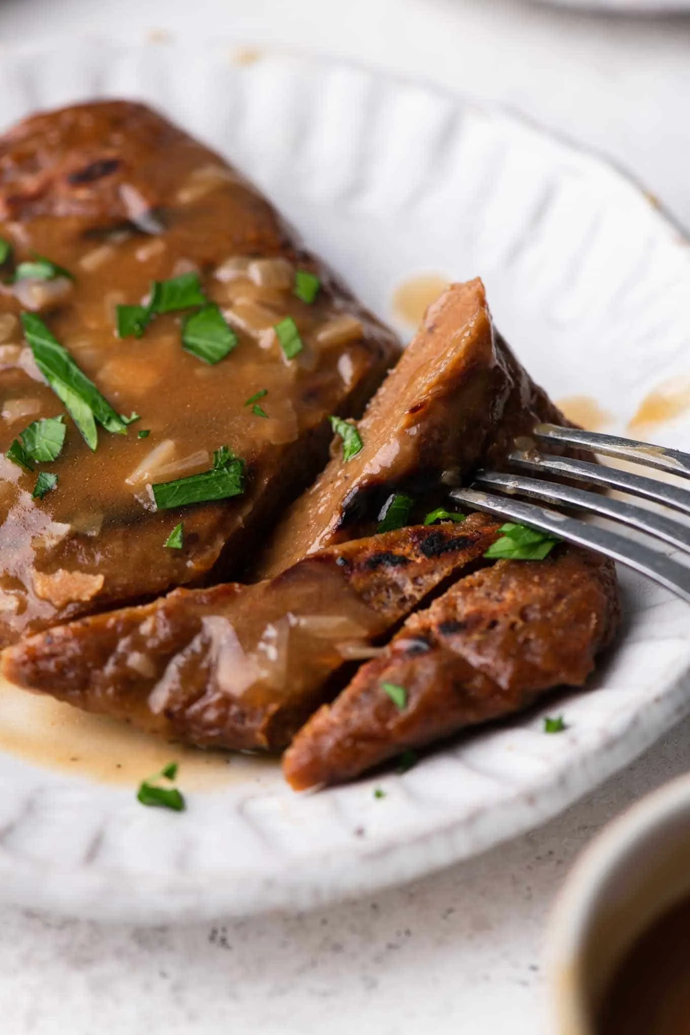 seitan steak topped with gravy and parsley with some bites cut and one on a fork