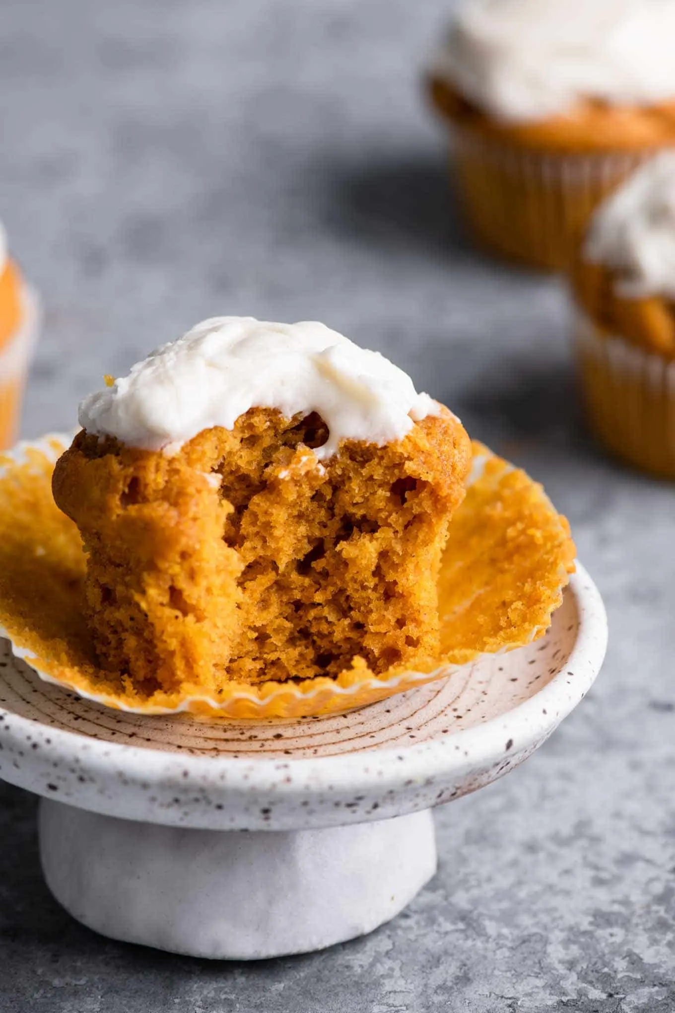 vegan pumpkin muffin with bite taken out on a mini cake stand