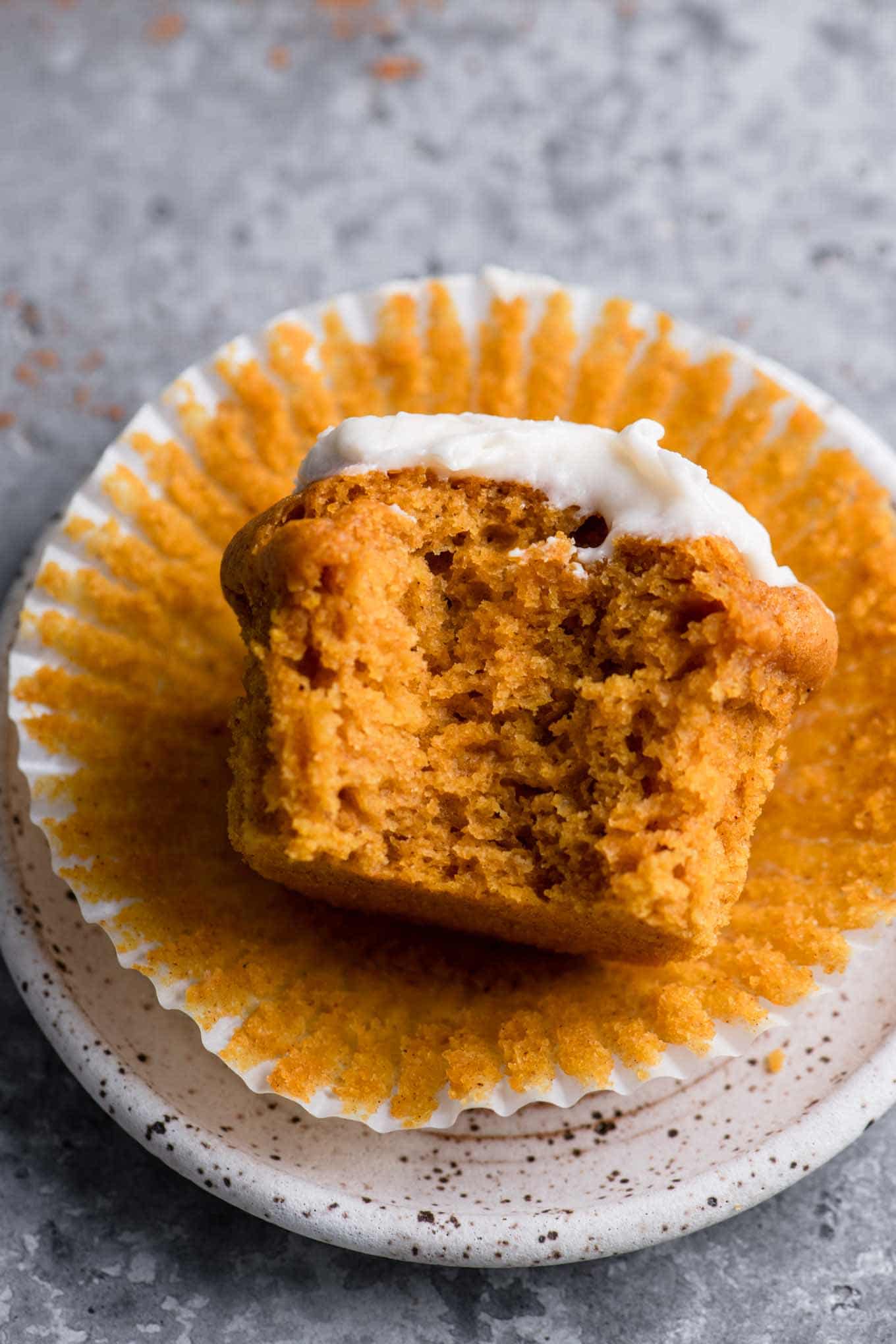 cream cheese frosted vegan pumpkin muffin with bite taken out