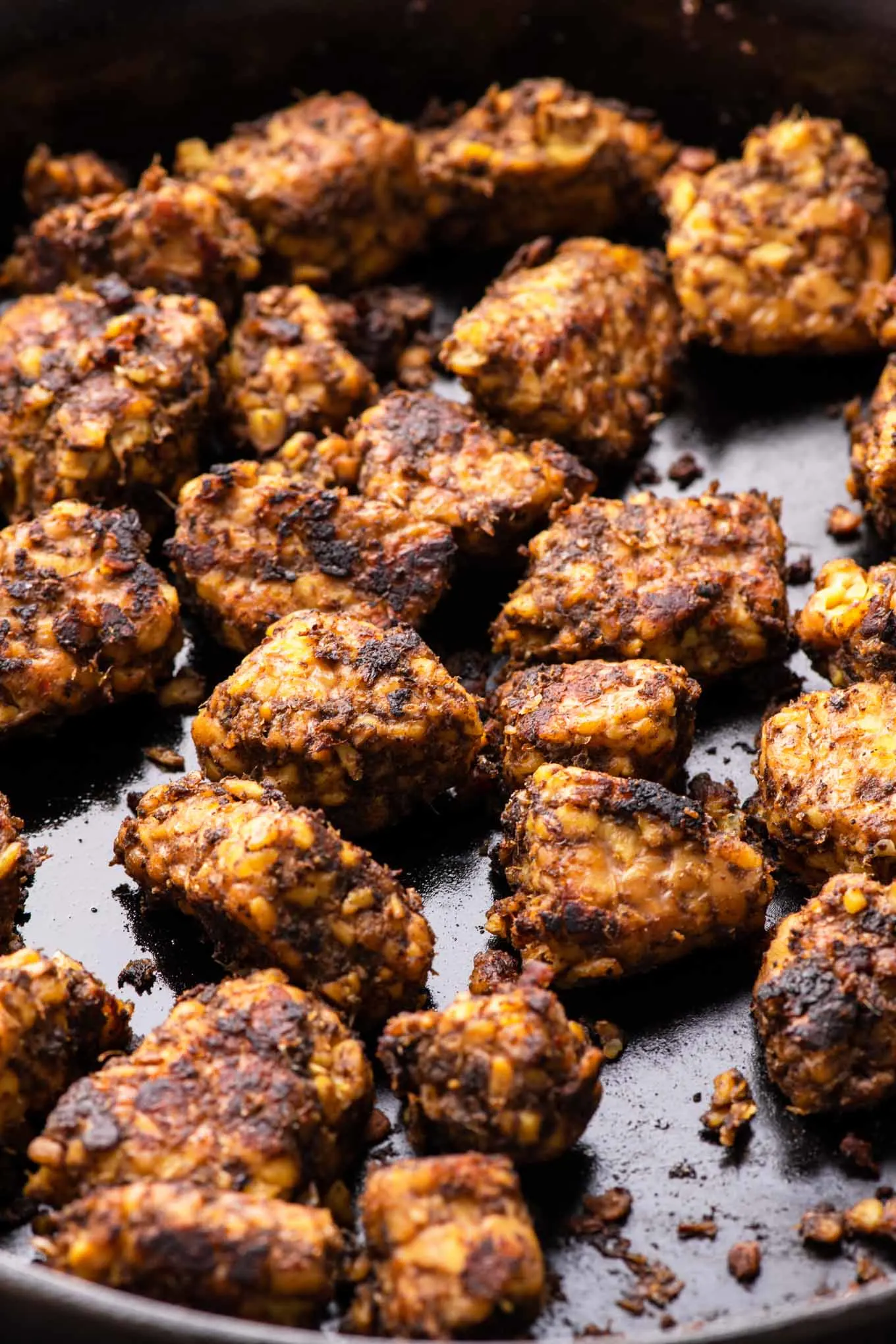 backlit view of jerk tempeh in cast iron skillet