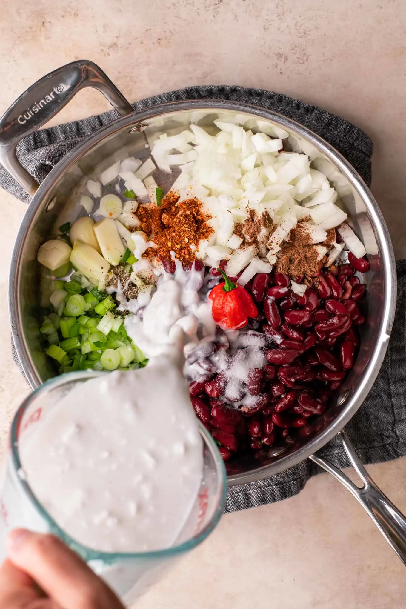 pouring coconut milk into ingredients for red beans and rice