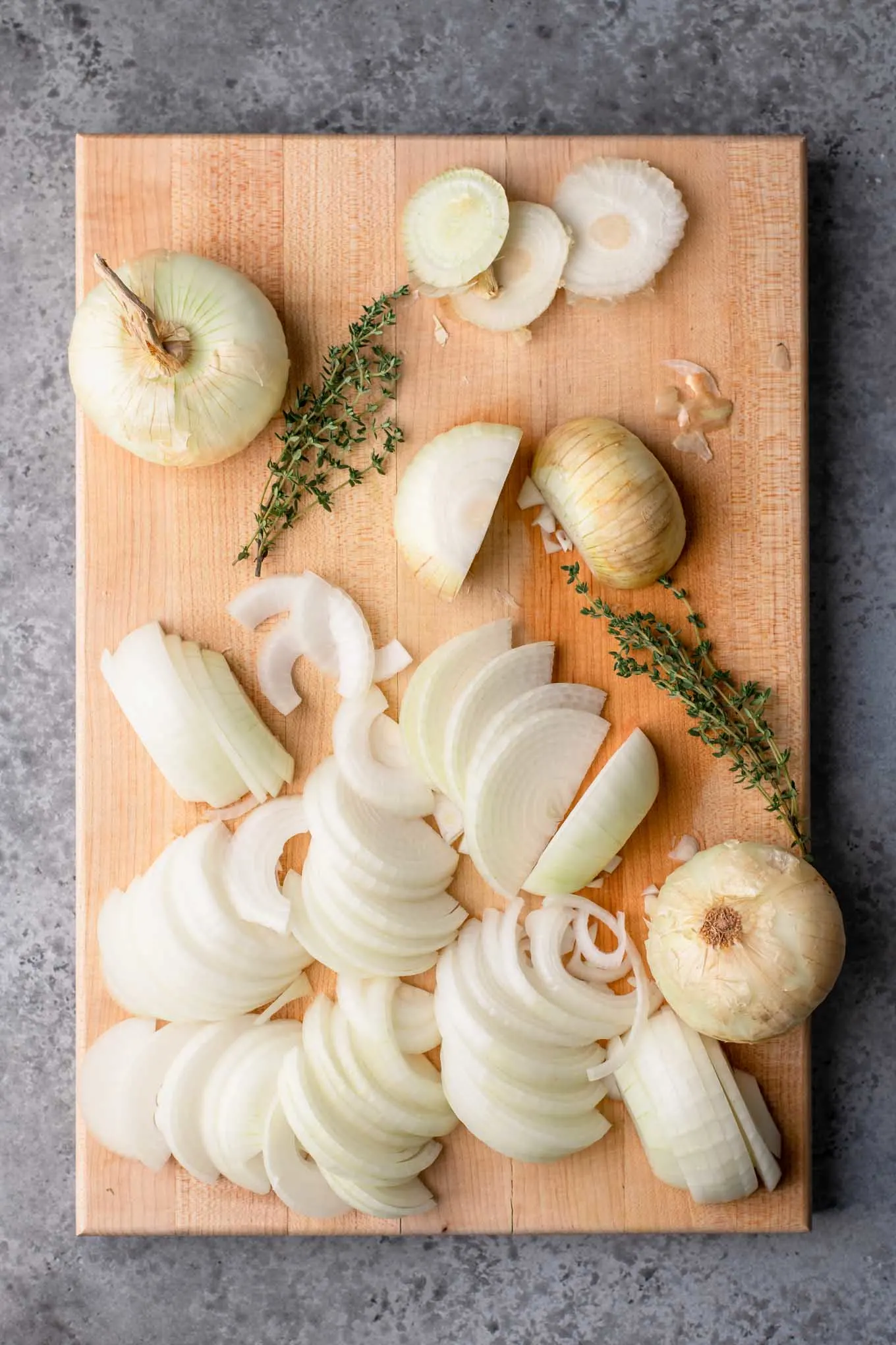 sweet onions on cutting board being slice into half moons