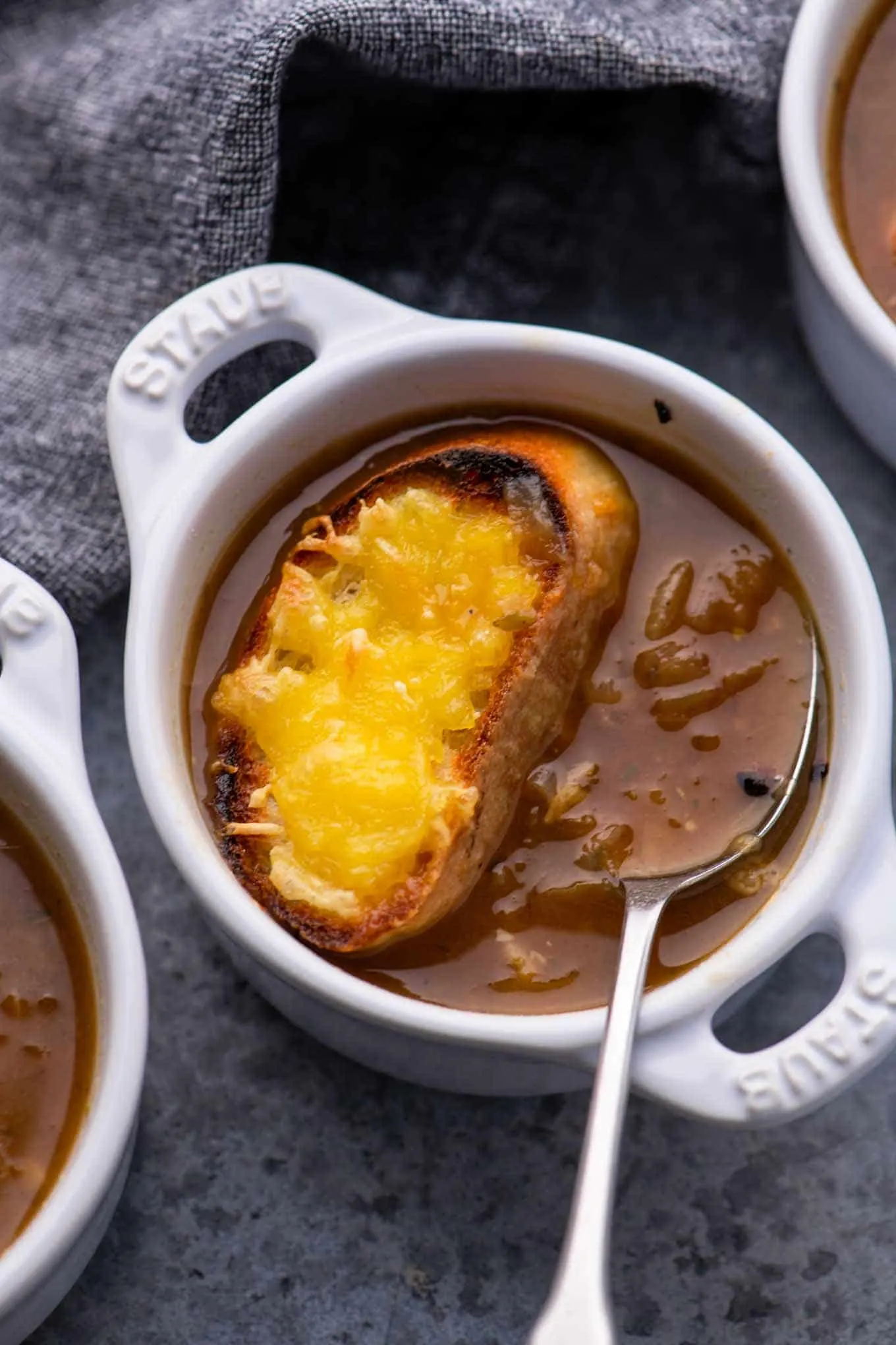 small bowl of soup with cheesy crouton on top and spoon lifting up soup